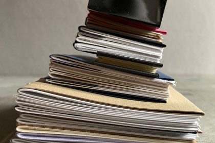 A pile of freshly bound sketchbooks with a chrome paperweight on top