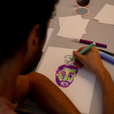 Self-portrait workshop: participant drawing face in greens and purples