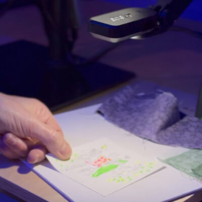 Lydia placing a sketch under the camera of a piece of tech on show at Flux Innovation Lounge