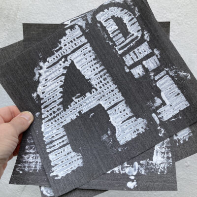 Cardboard relief prints of letterforms drawn from foundation stones, in emulsion on wall paper