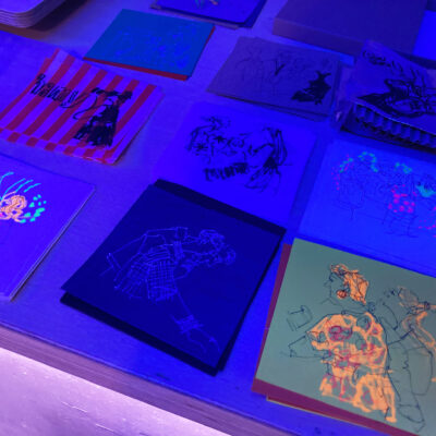 Sketches photographed flat as a group, some glowing in the blue light